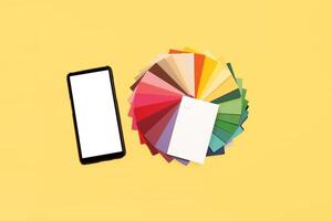 Top view of colorful samples and smartphone with blank screen on yellow background. photo