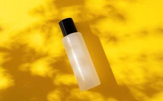 white bottle of cosmetic, shampoo, gel on a yellow background. Place for text. Hard shadows. Copy space. background with tropical plant shadow. photo