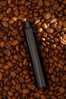 Coffee beans background and E-cigarette. Coffee flavored vape juice concept photo