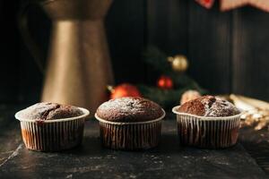 chocolate muffins with powdered sugar on top on a black background. Christmas decoration . Still life close up. Food photo