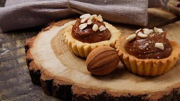 dulce chocolate magdalenas y galletas nuez con condensado Leche en un de madera estar con arpillera en el mesa. todavía vida foto