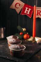 chocolate muffins with powdered sugar on top on a black background. Christmas decoration . Still life close up. Food photo