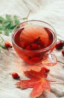 A cup of rose hip tea with fresh berries in a glass cup. Vintage background, selective focus photo