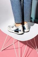 Summer women's shoes on a colored background. The model is standing on a chair. Light shoes with spikes. rear view. photo