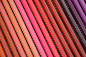 A set of Colored pencils lying in a beautiful gradient transition from yellow to pink and red, brown and purple hues. Abstract background. photo