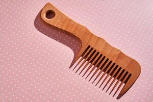 Wooden comb on a pink polka dot background. photo