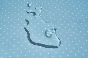 A drop of water or cosmetic serum on a blue polka dot background. photo