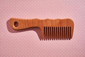 Wooden comb on a pink polka dot background. photo