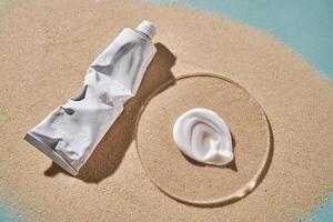 A tube of moisturizing sunscreen and a smear on a sandy background. photo