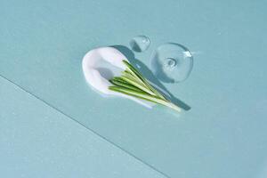 A smear of cream with rosemary and drops of serum on a blue background. photo