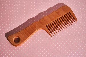 Wooden comb on a pink polka dot background. photo