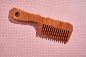 Wooden comb on a pink polka dot background. photo