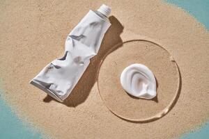 A tube of moisturizing sunscreen and a smear on a sandy background. photo