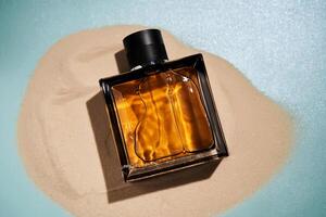 A bottle of perfume on a background of sand. photo