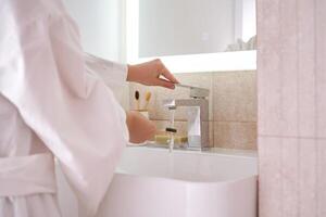 Women's hands under running water in the bathroom. Morning routine. photo