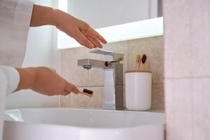 Women's hands under running water in the bathroom. Morning routine. photo