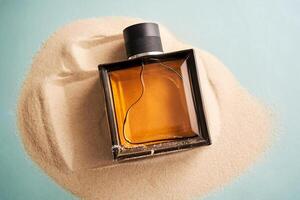 A bottle of perfume on a background of sand. photo