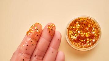 Cosmetic gel with glitter on women's fingers on a beige background. photo