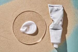 A tube of moisturizing sunscreen and a smear on a sandy background. photo