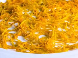 Fresh orange zest on a white plate. Raw citrus zest, grated orange peel, fresh zest on a white background. photo