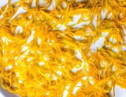 Fresh orange zest on a white plate. Raw citrus zest, grated orange peel, fresh zest on a white background. photo