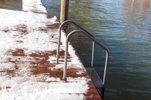 pequeño de madera muelle en el nieve con escalera a lago traunsee en Austria. foto