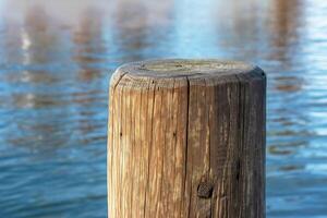 A pier made of wooden piles for mooring boats and maintaining the stability of the pier against the backdrop of water Lake Traunsee in Austria. photo