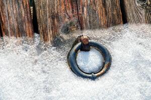 An anchor iron ring at a snowy harbour. photo