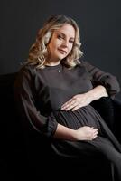 Pregnant Woman Posing In An Elegant black Dress indoors studio black wall background photo