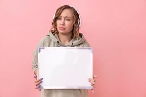 Woman holding empty blank board over pink background photo