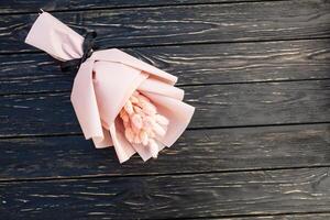 Beautiful bouquet of dry pink flowers on a wooden black background. Minimalism, space for text. Gift Card photo