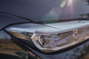 Front lights of a black city car, modern car lights close view background photo