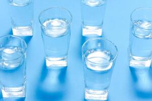 Glasses of water on a paper background. Drawing shadows. Classic Blue color. clean water concept photo