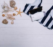 Beach accessories. Towel, flip-flops, starfish, boat and sunglasses on wooden background. Top view with copy space. Sunny toned photo