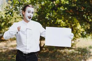 Your text here. Actors mimes holding empty white letter. Colorful portrait with green background. April fools day photo