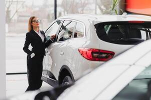 hermosa joven mujer compra un coche en el concesión salón. foto