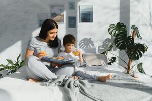 Beautiful woman with her son drinking juice in the morning in bed. Healthy eating concept photo