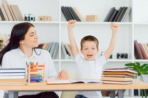 Portrait of handsome boy at workplace with his tutor sitting near by and telling something photo