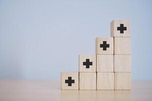 Stacked wooden blocks with a plus sign It represents economic concepts and positive thinking concepts. photo