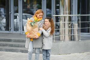 familia compras. madre y su hija son participación tienda de comestibles compras bolso con vegetales foto