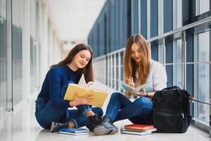 hembra estudiantes sentado en el piso y leyendo notas antes de examen foto