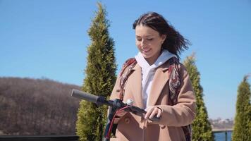 ein jung Mädchen Mieten elektrisch Roller mit Handy, Mobiltelefon Telefon App. Tourist Telefon Anwendung. modern Gadgets zum jung Menschen und Geschäft Menschen video