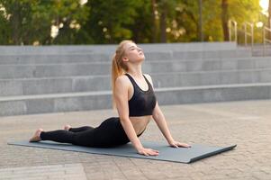 Fitness Woman Practice Yoga Exercises On Mat Outdoor City Street Sunlight Background photo