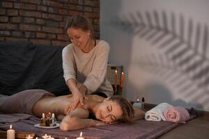 relajarse y disfrutar en spa salón, consiguiendo masaje por profesional masajista. mujer acostado con desnudo espalda relajarse en piso cobija foto