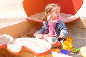 Cute little caucasian girl on the playground, happy child with pleasure spending time outdoors, happy carefree childhood photo