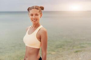 Refreshing wild sea side workout. smiling healthy fitness woman in sports gear on the beach looking into the distance photo