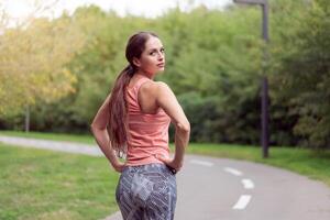 Beautiful athletic woman standing running track in summer park Portrait caucasian female jogger outdoor photo