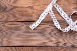 White measuring tape of a tailor lies in corner on dark wooden background. photo