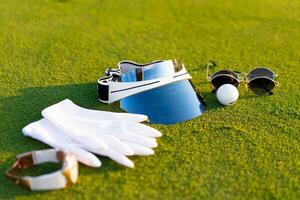 Luxury golf equipment white gloves sunglasses watch ball sun cap lying on green golf grass photo