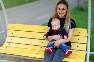 hermosa joven madre camina con su pequeño hijo en un verano parque foto